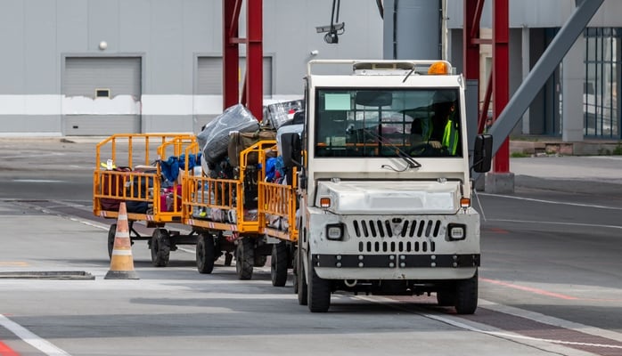 Tow tractor pulling luggage cart at airport